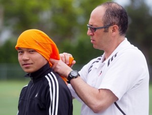Coach Ihab Leheta helps soccer player Shokhab Haydari with the FC Brossard U14AA team, put on a turban prior to soccer practice on Monday June 10, 2013 at Poly-Arena park in Brossard.